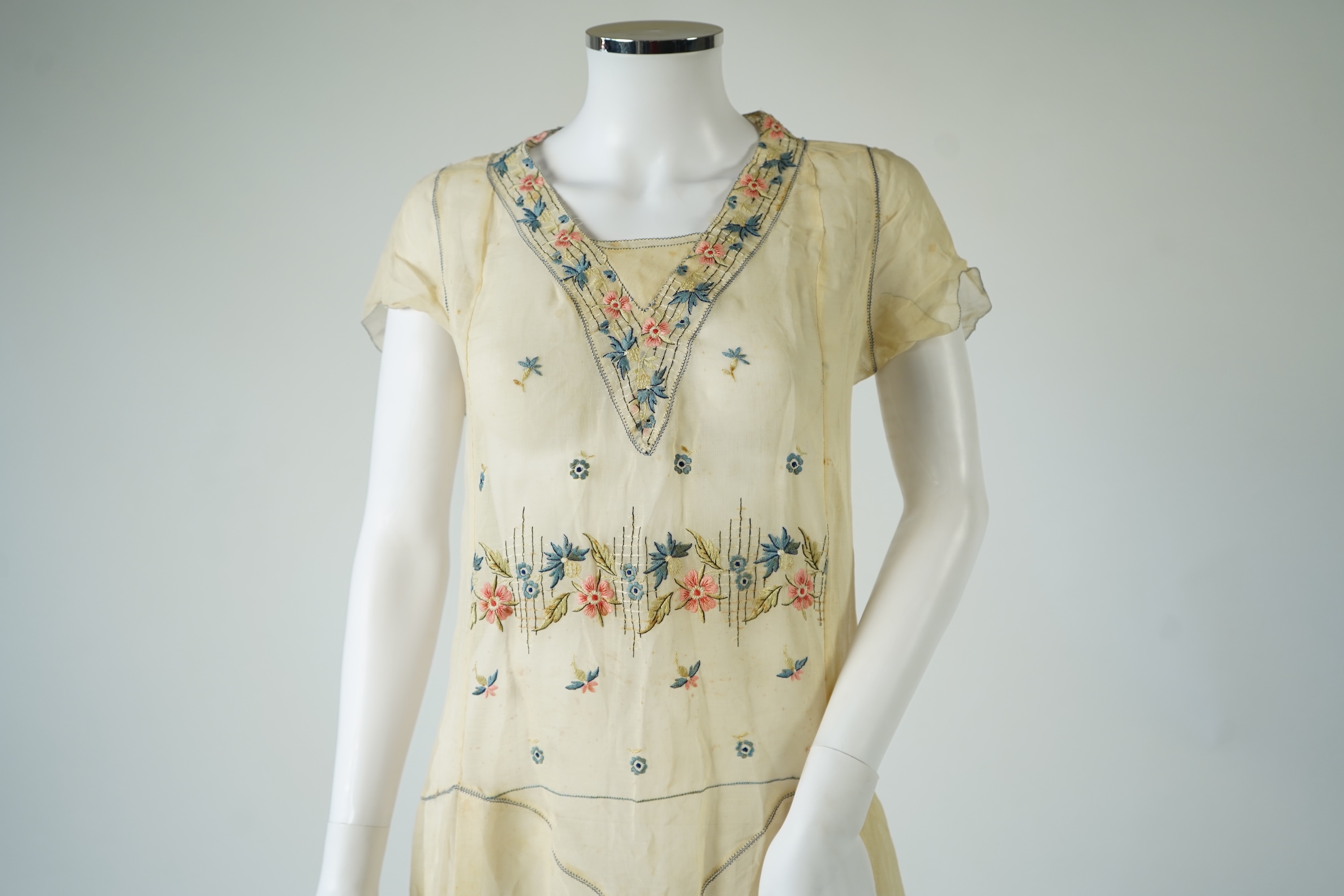 An unusual 1920's fine cream lawn summer dress with hand embroidered blue, pink, flowers, tie and picot edging., 116cm long. Condition - some small rust stains and one small tear at the back right shoulder.